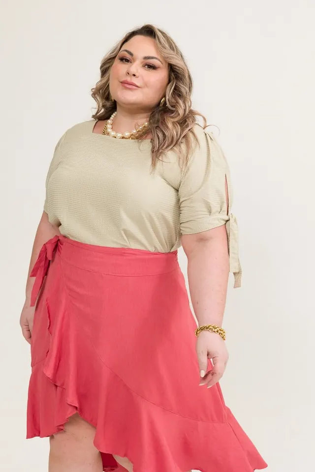 Plus size model wearing a beige blouse and a coral ruffled skirt