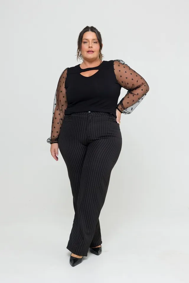 Plus size model wearing a black blouse with sheer sleeves and black trousers