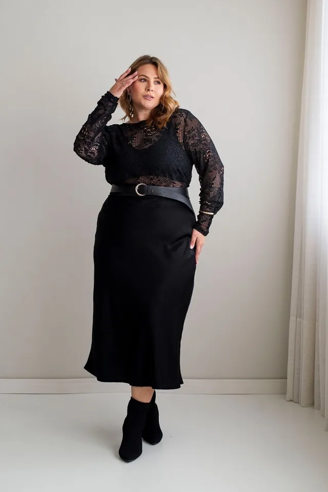 Plus size model wearing a black satin midi skirt and lace top
