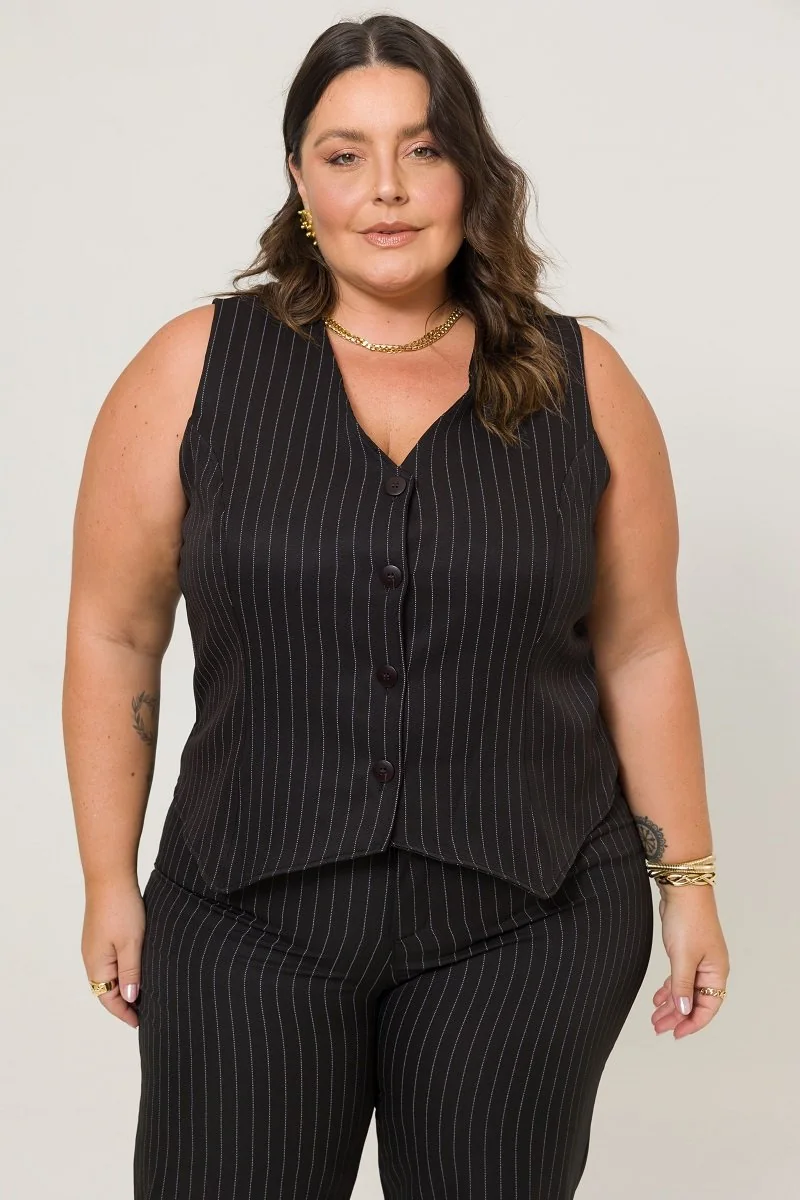 Plus size model wearing a black pinstripe vest and trousers